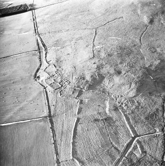 Oblique aerial view centred on the remains of the fermtoun with the remains of the buildings and hut circles, taken from the SE.