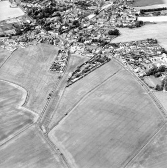 Oblique aerial view centred on the cropmarks of the S end of the Roman Temporary Camp with possible unenclosed settlements and town adjacent, taken from the E.