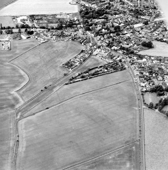 Oblique aerial view centred on the cropmarks of the S end of the Roman Temporary Camp with possible unenclosed settlements and town adjacent, taken from the ENE.