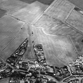 Oblique aerial view centred on the cropmarks of the S end of the Roman Temporary Camp with possible unenclosed settlements and town adjacent, taken from the NW.