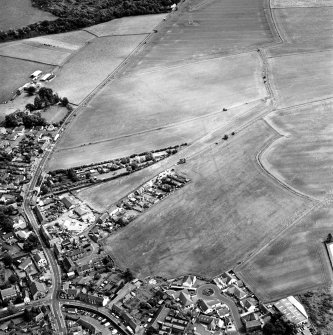 Oblique aerial view centred on the cropmarks of the S end of the Roman Temporary Camp with possible unenclosed settlements and town adjacent, taken from the SW.