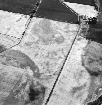 Oblique aerial view centred on the cropmarks of the pit-defined cursus, pits and rig, with farmhouse, pits, rig, ring-ditch and possible quarry adjacent, taken from the W.