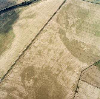 Oblique aerial view centred on the cropmarks of the pit-defined cursus, pits and rig, with pits, rig, ring-ditch and possible quarry adjacent, taken from the ENE.