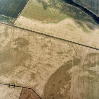 Oblique aerial view centred on the cropmarks of the pit-defined cursus, pits and rig, with pits, rig, ring-ditch and possible quarry adjacent, taken from the NNW.