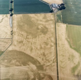 Oblique aerial view centred on the cropmarks of the pit-defined cursus, pits and rig, with farmhouse, pits, rig, ring-ditch and possible quarry adjacent, taken from the W.