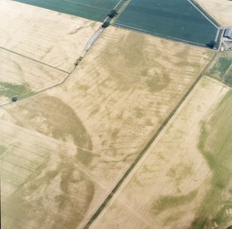 Oblique aerial view centred on the cropmarks of the pit-defined cursus, pits and rig, with pits, rig, ring-ditch and possible quarry adjacent, taken from the SW.