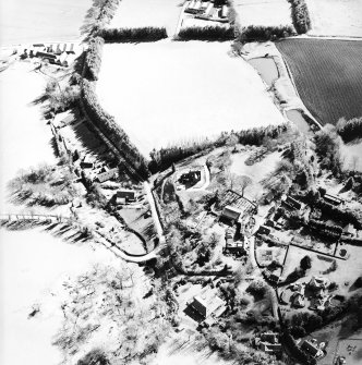Oblique aerial view centred on the remains of the motte and the church and burial-ground, taken from the NW.
