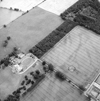 Oblique aerial view centred on the cropmarks of the ring-ditch with country house adjacent, taken from the S.