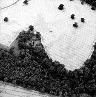 Oblique aerial view centred on the cropmarks of the enclosures and pits, with the church, burial-ground and mausoleum adjacent, taken from the E.