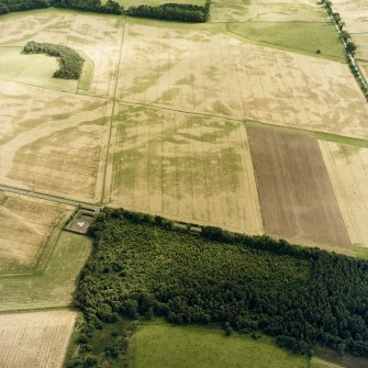 Oblique aerial view centred on the cropmarks of the pit-defined enclosure with the cropmarks of the barrow and pits, adjacent, taken from the NW.