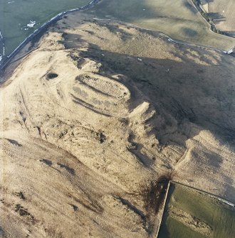 Oblique aerial view centred on the remains of the fort with rig adjacent, taken from the SE.