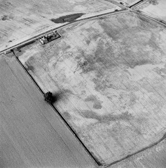 Oblique aerial view centred on the cropmarks of an enclosure with possible unenclosed settlement adjacent, taken from the SSW.