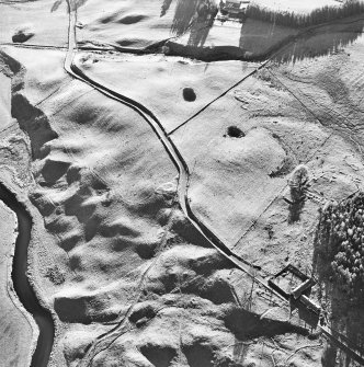 Oblique aerial view centred on the remains of a hut circle with three farmsteads, ring ditch house and farmsteading adjacent, taken from the NNE.