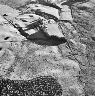 Oblique aerial view centred on the remains of a farmstead with farmsteads, farmsteading, possible hut circle, buildings and banks adjacent, taken from the NNW.