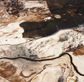 Oblique aerial view centred on the remains of ring-ditch houses, rig and small cairns with banks, rig, small cairn, farmsteads and buildings adjacent, taken from the E.