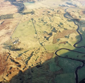 Oblique aerial view centred on the remains of buildings, enclosures and small cairns with township, buildings, small cairns, farmsteading, cairn, hut-circles, banks and huts adjacent, taken from the NW.