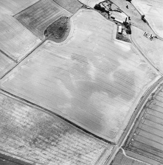 Oblique aerial view centred on the cropmarks of the ring-ditches, unenclosed settlement and barrow with the farmstead adjacent, taken from the NNE.