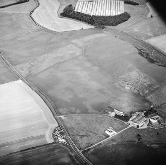 General oblique aerial view centred on the cropmarks of the ring-ditches, unenclosed settlement, enclosures and possible enclosures with the farmhouse and farmsteading adjacent, taken from the WSW.