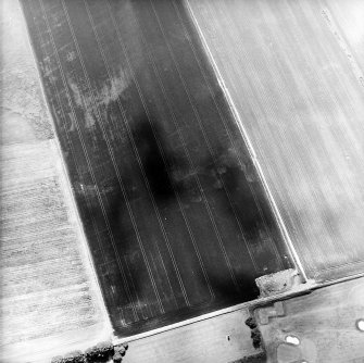 Oblique aerial view centred on the cropmarks of the ring-ditches, enclosures and rig with the war memorial adjacent, taken from the NNE.