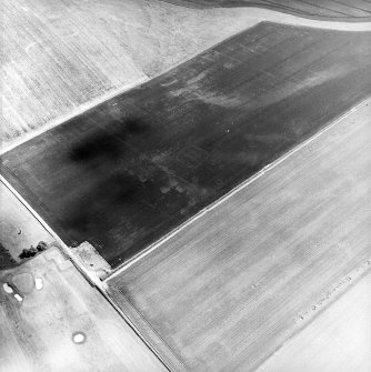Oblique aerial view centred on the cropmarks of the ring-ditches, enclosures and rig with the war memorial adjacent, taken from the NW.