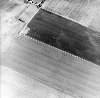Oblique aerial view centred on the cropmarks of the ring-ditches, enclosures and rig with the war memorial adjacent, taken from the SW.