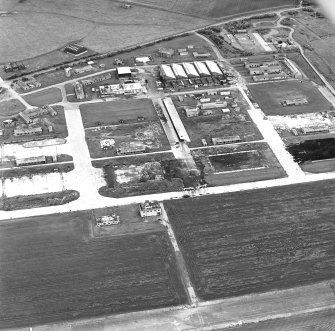 Oblique aerial view of Crail Airfield centred on the remains of the control tower, buildings, huts and aircraft hangars, taken from the ESE.