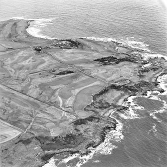 Oblique aerial view centred on the remains of the linear earthwork with farm, building and coastguard station adjacent, taken from the S.