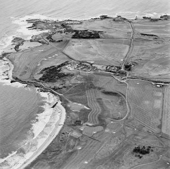 Oblique aerial view centred on the remains of the linear earthwork with farm, building and coastguard station adjacent, taken from the NW.
