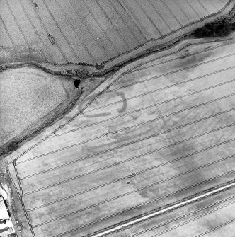 Oblique aerial view centred on the cropmarks of the enclosure, pits, rig and field boundary, taken from the SSE.