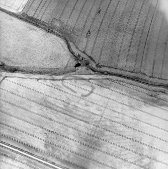 Oblique aerial view centred on the cropmarks of the enclosure, pits, rig and field boundary, taken from the SE.