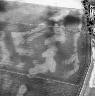 Westfield, oblique aerial view, taken from the SW, centred on the cropmarks of rig, a souterrain, pits and a possible round house. The cropmark of an enclosure is visible in the top left-hand corner of the photograph.