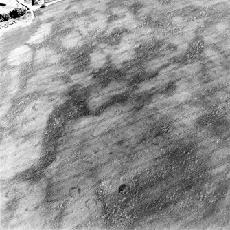 Oblique aerial view centred on the cropmarks of a pit-defined enclosure with unenclosed settlement and souterrains adjacent, taken from the WNW.