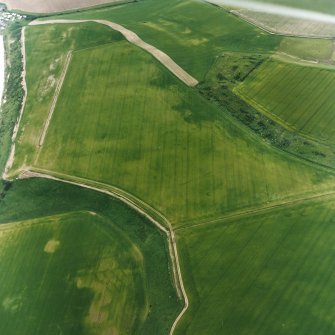 Oblique aerial view centred on the cropmarks of the unenclosed settlement, enclosures, possible souterrains, linear cropmarks and possible field boundaries, taken from the NNW.