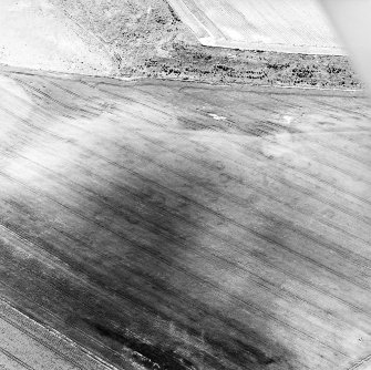 Oblique aerial view centred on the cropmarks of an unenclosed settlement, enclosures and possible souterrains, taken from the NE.