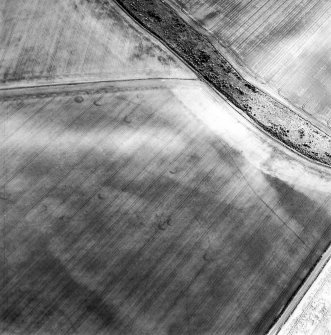 Oblique aerial view centred on the cropmarks of the unenclosed settlement, linear cropmarks and souterrains, taken from the NNW.