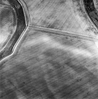 Oblique aerial view centred on the cropmarks of the unenclosed settlements, linear cropmarks, souterrains, possible field boundaries and field system, taken from the NW.