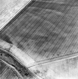 Oblique aerial view centred on the cropmarks of the unenclosed settlement, linear cropmarks and souterrains, taken from the SSE.