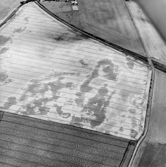 Oblique aerial view centred on the cropmarks of the unenclosed settlements, pit-alignment, pits and rig, taken from the NE.