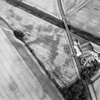 Oblique aerial view centred on the cropmarks of the enclosure, pits, rig and ring-ditch, with the farmhouse and farmsteading adjacent, taken from the WNW.