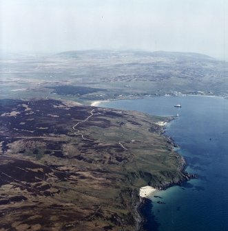 General oblique aerial view looking across the remains of the farmstead, townships and lazy-beds towards Kilnaughton Bay and the S of Islay with the Paps of Jura beyond, taken from the SW.