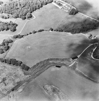 Oblique aerial view centred on the remains of the cairn, cropmarks of the possible field boundaries and further cropmarks, taken from the SE.