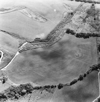 Oblique aerial view centred on the remains of the cairn, cropmarks of the possible field boundaries and further cropmarks, taken from the NNW.