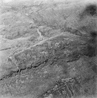Oblique aerial view centred on the remains of the fort with rig and field banks adjacent, taken from the ESE.