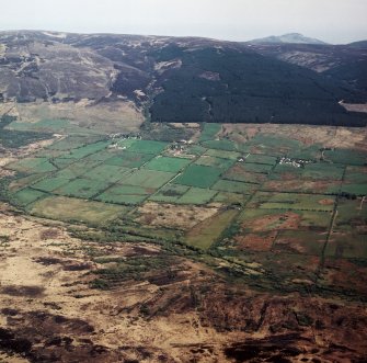 General oblique aerial view looking across Machrie Moor towards the field system and farmsteads with Beinn Bhreac beyond, taken from the WNW.