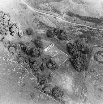 Oblique aerial view centred on the remains of the burial-ground and church, taken from the SW.