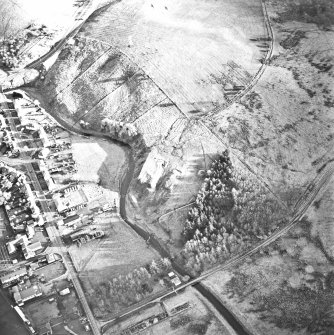 Oblique aerial view centred on the remains of the coal mine with the enclosure adjacent, taken from the N.