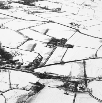 Distant oblique aerial view centred on the farmsteading with rig adjacent, taken from the W