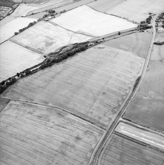 Oblique aerial view centred on the cropmarks of the Antonine Wall and the site of the Roman fortlet, taken from the NE.