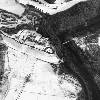 Oblique aerial view centred on the hunting lodge and ornamental gardens with the remains of a castle adjacent, taken from the NW.