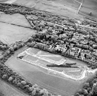 Oblique aerial view centred on the excavations at Dullatur Roman Camps with the Antonine Wall nearby, taken from the ESE